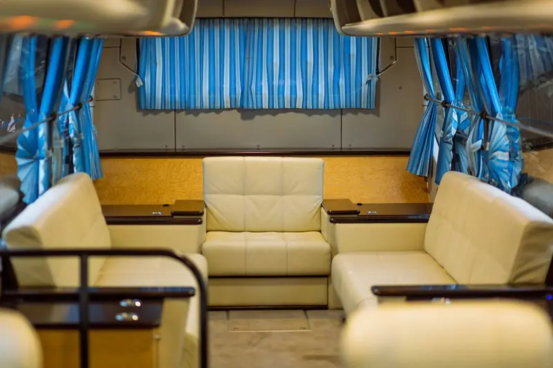 Spacious and luxurious van interior featuring leather seats and blue curtains