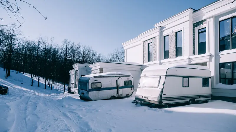 White trailers parked beside a snow-covered building under a clear blue sky, evoking winter tranquility