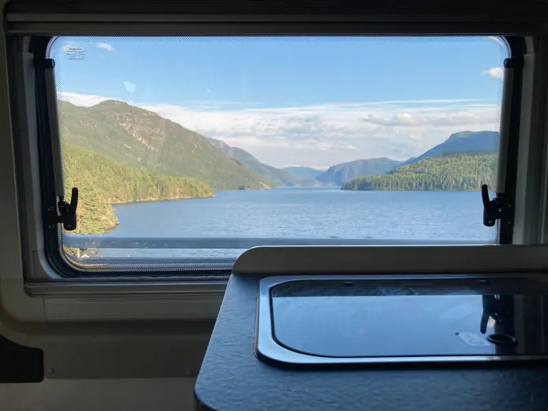 Enjoy a stunning view of a serene mountain lake through a camper van window