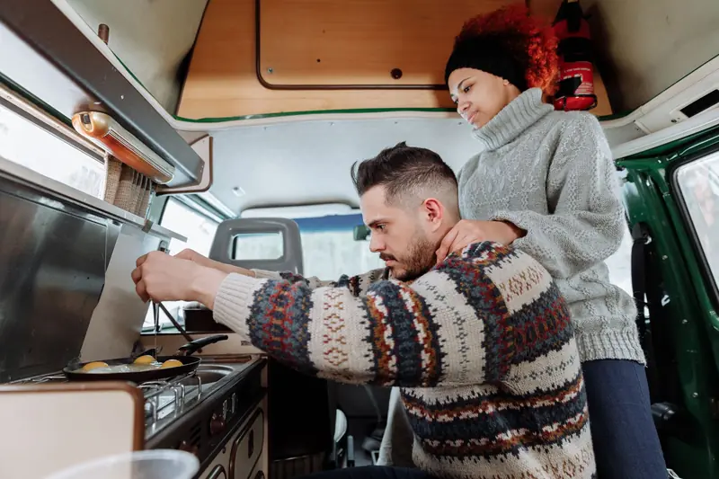 Interracial couple cooking breakfast in cozy camper van during a road trip adventure