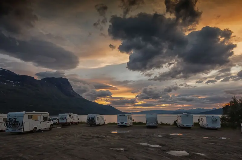 Stunning sunset view over a scenic Norwegian campsite with parked RVs and dramatic clouds