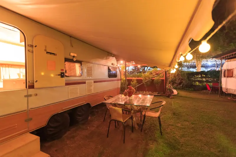 Relaxing night scene of an outdoor RV setup with ambient lighting and a dining table
