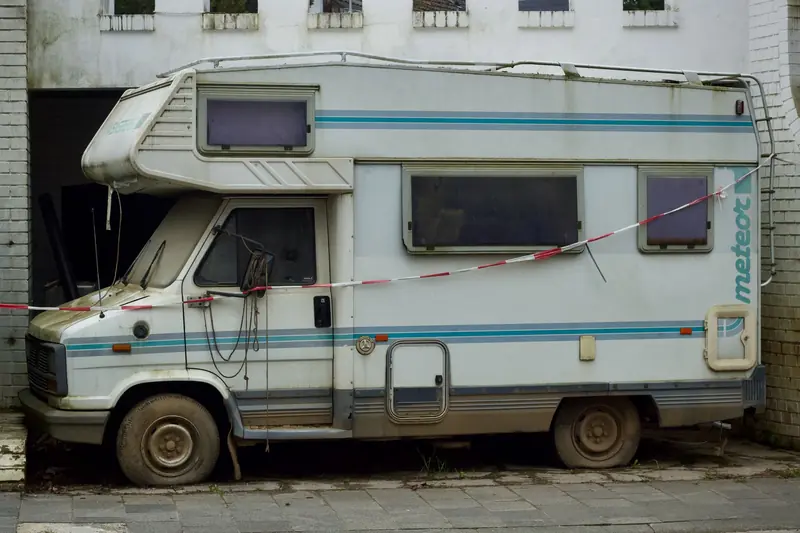 An old, abandoned camper van parked in an alleyway, showcasing urban decay