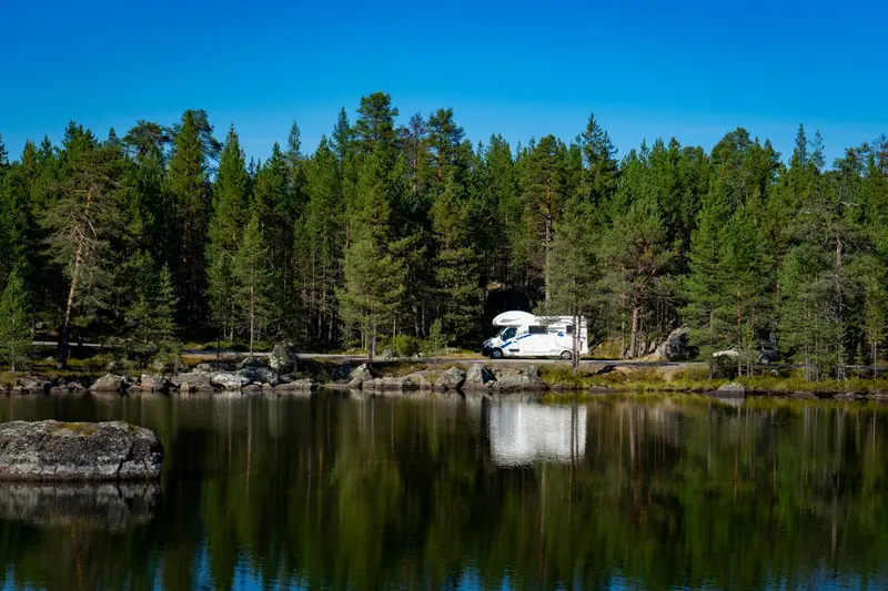 Beautiful lake reflection of forest and camper van in Troms, capturing serene nature