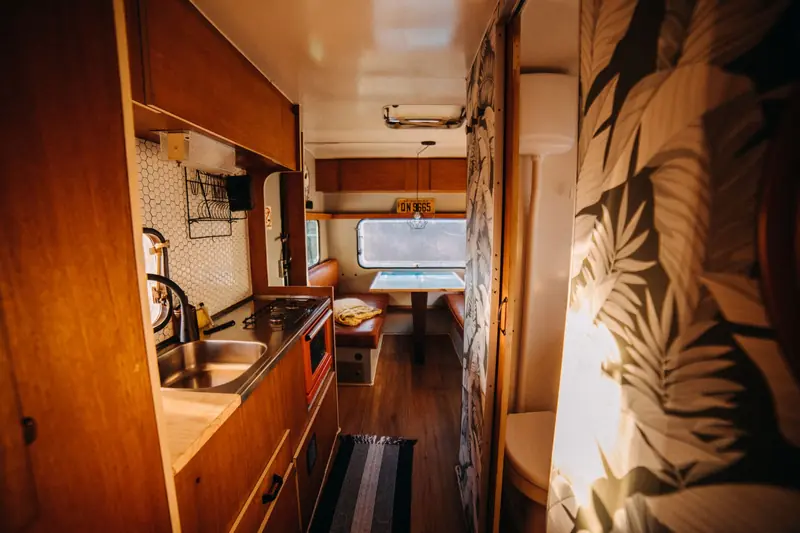 Warm and inviting camper kitchenette with retro decor, showcasing a cozy dining area and modern amenities