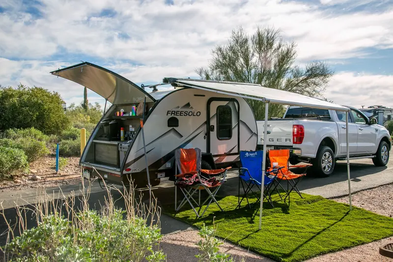 A scenic campsite in Apache Junction, AZ showcasing a Freesolo motorhome with camping chairs and pickup truck