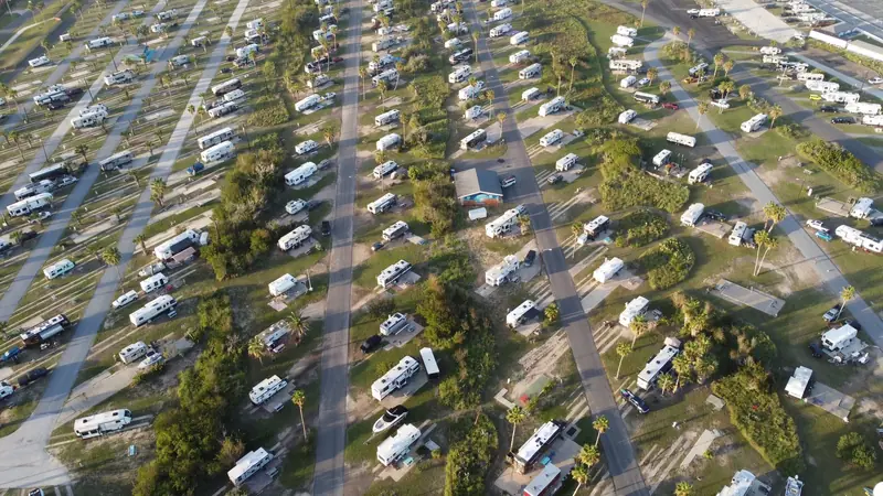 Aerial shot of a lush campsite filled with RVs and trailers during the day