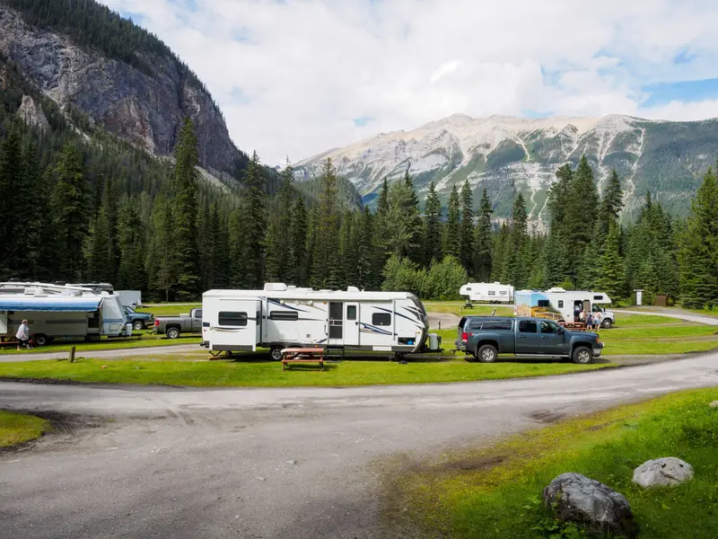 A beautiful campsite featuring RVs amidst lush forests and towering mountains for a peaceful getaway